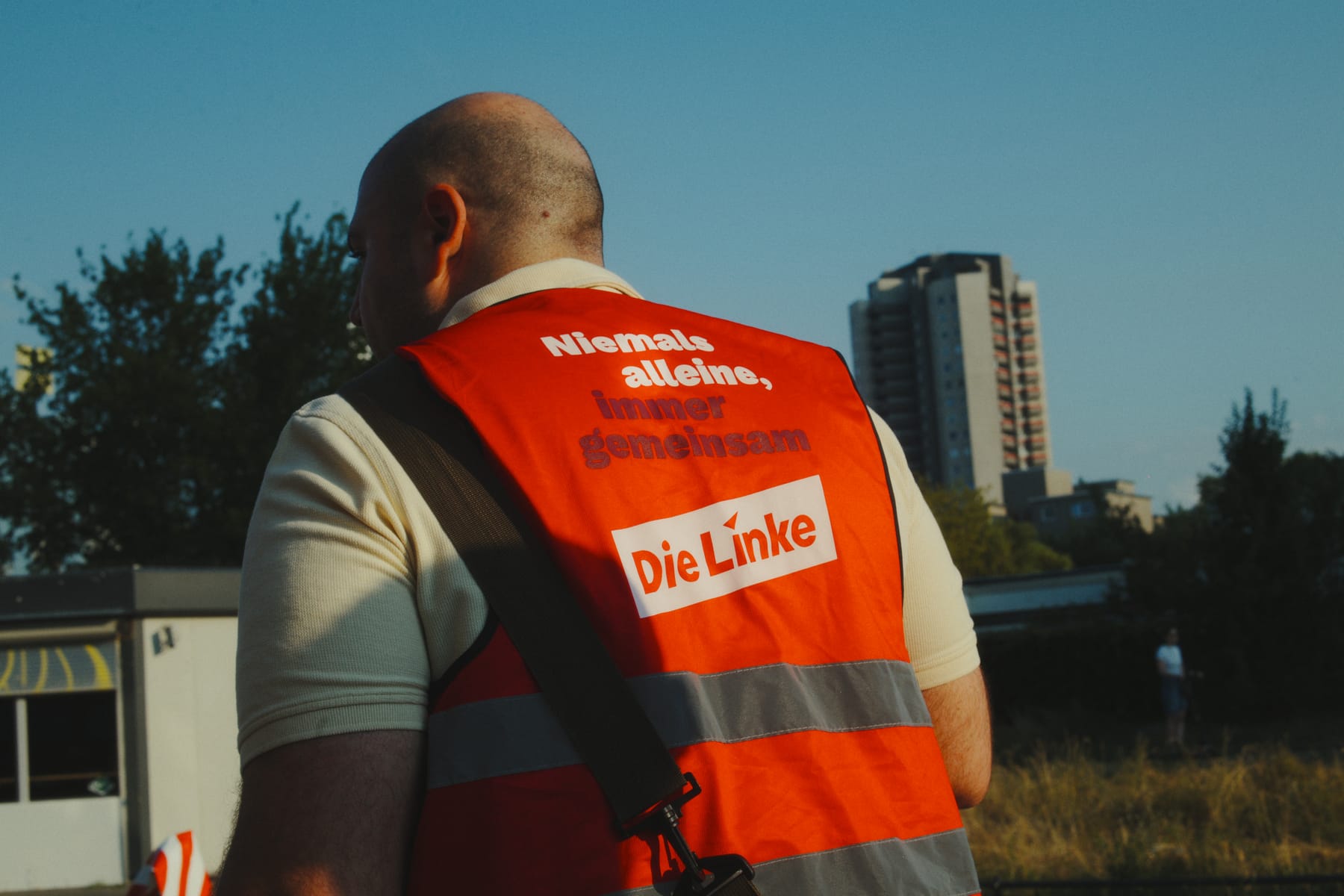 Wahlkampfweste mit der Aufschrift „Niemals alleine, immer gemeinsam — Die Linke" vor einem Hochhaus